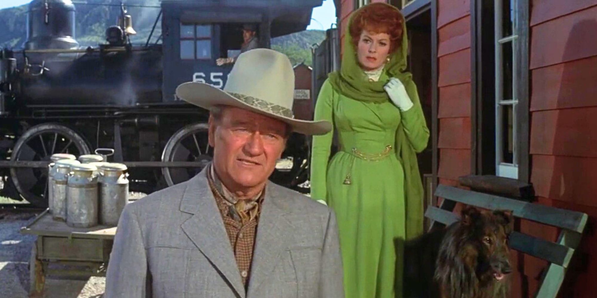 Maureen O'Hara standing behind John Wayne at a railroad station in Big Jake (1971)