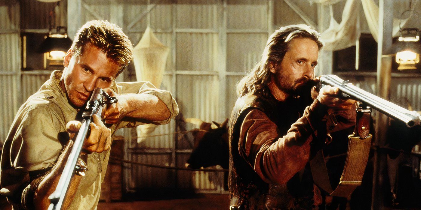 A short-haired man stands next to a long-haired man as both men hold long rifles pointed at lions off-camera