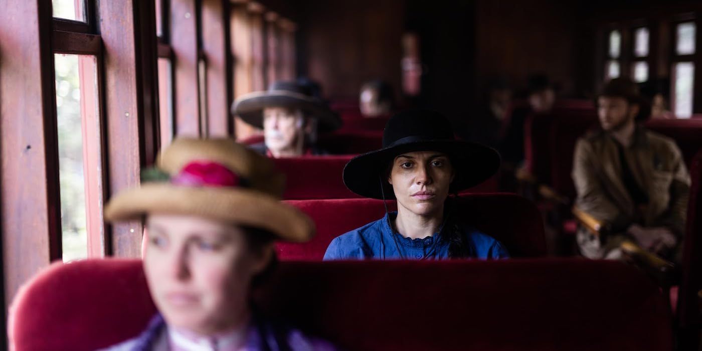 Celeste Wall está sentada tranquilamente en un tren, mirando al frente en la película 