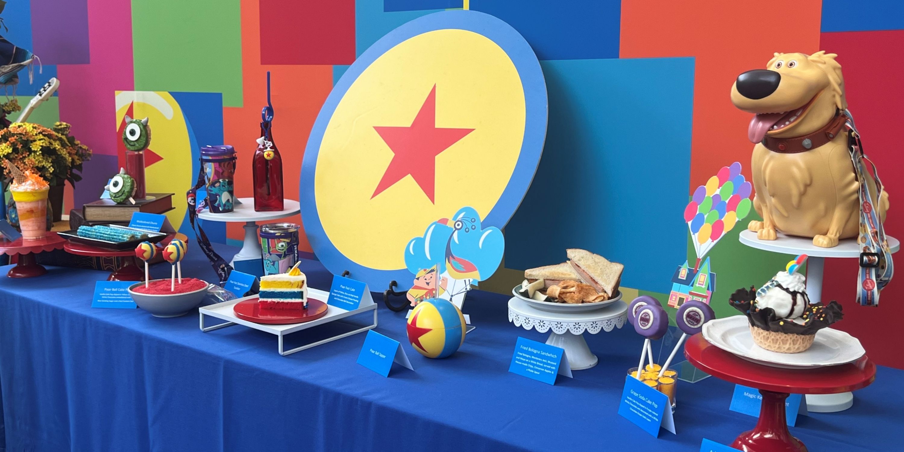 A Pixar Fest display of select food and beverage offerings and the Dug popcorn bucket at Disneyland Resort