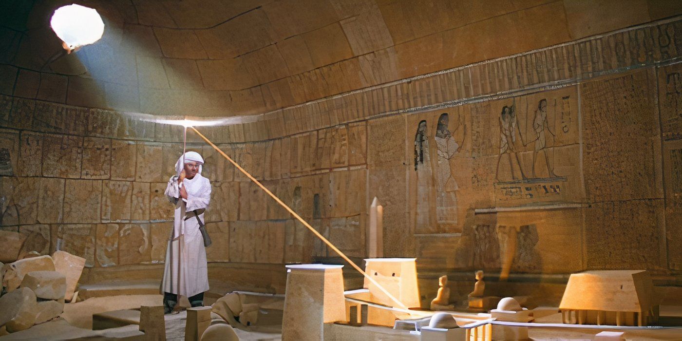 Indiana Jones stands in the map room as a beam of light shines through the Staff of Ra, illuminating a map