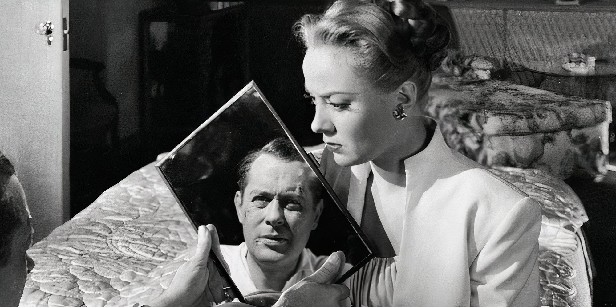 Robert Montgomery looking at himself in a pocket mirror while Audrey Totter is sitting across from him in Lady in the Lake (1947)