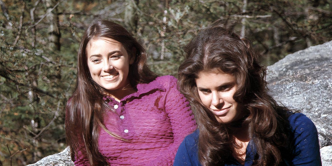 Sandra Peabody and Lucy Grantham smile sitting on a rock in the woods in The Last House on the Left (1972)