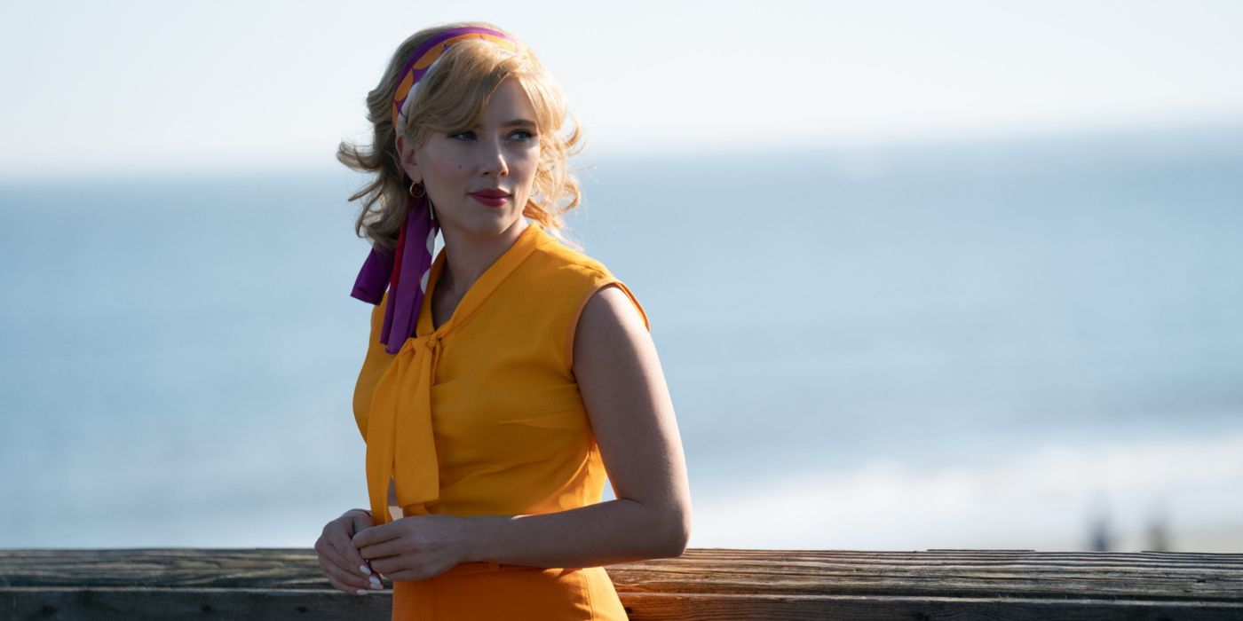 Scarlett Johansson wearing a yellow dress and smiling while standing on a dock in Fly Me to the Moon.