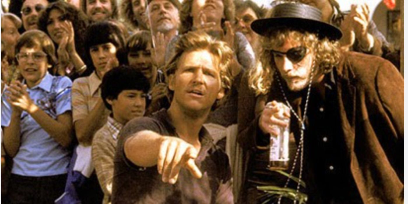 Jeff Bridges as Bone and John Heard as Cutter standing in a crowd and pointing in 'Cutter's Way'