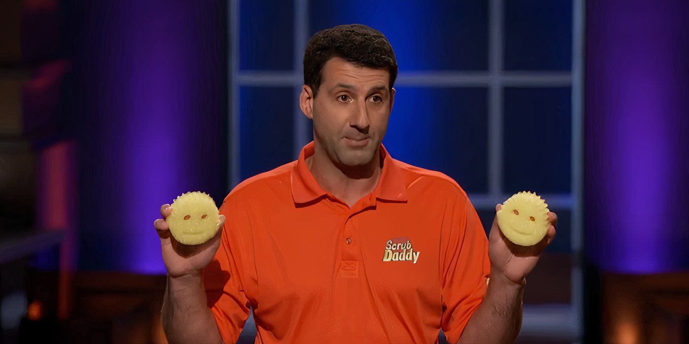 The owner of Scrub Daddy holding up two of the products, one in either hand, wearing an orange shirt on Shark Tank