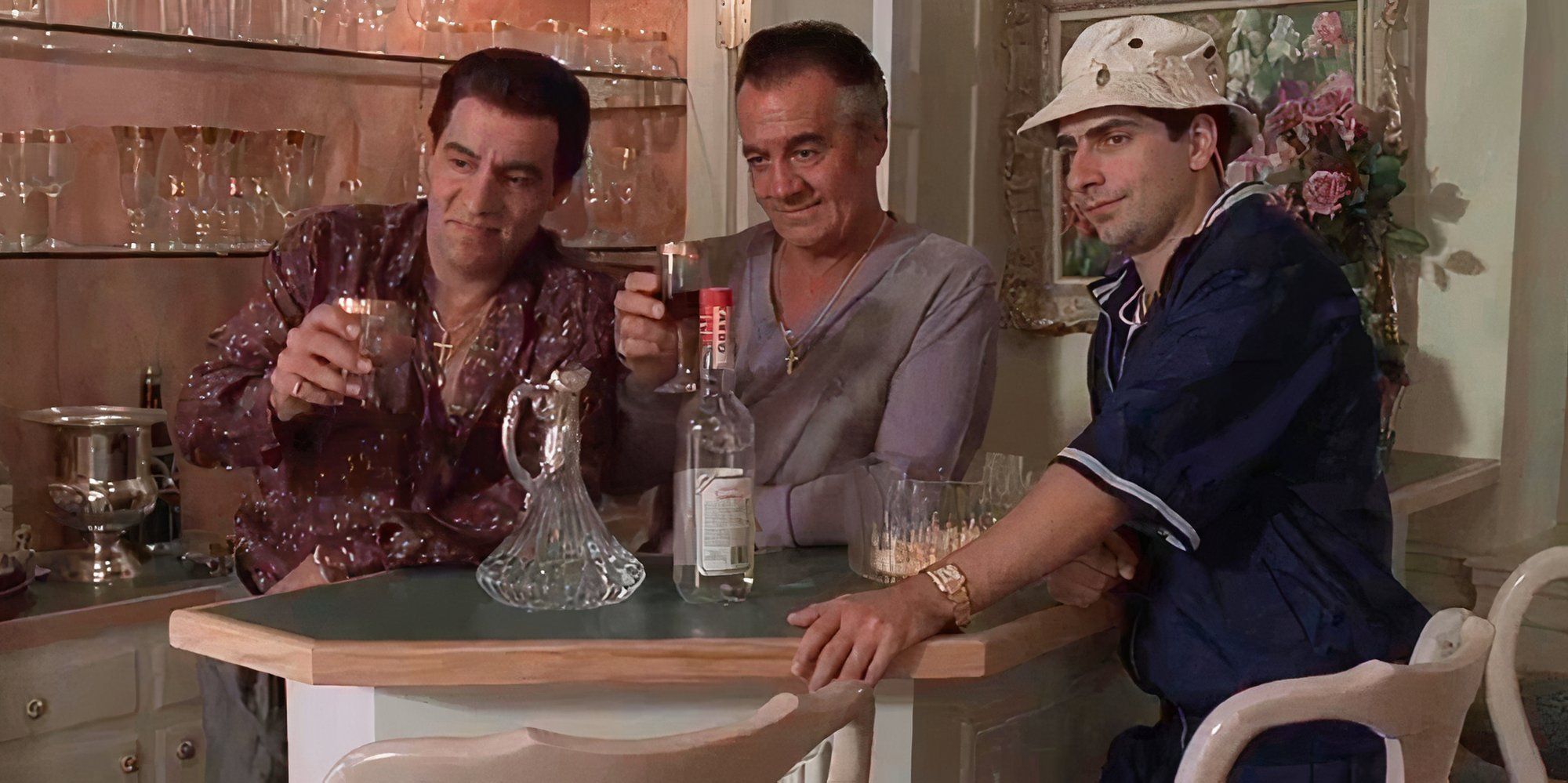 Steven Van Zandt and Tony Sirico holding drinks up in their hands while Michael Imperioli stands with them around a bar in The Sopranos