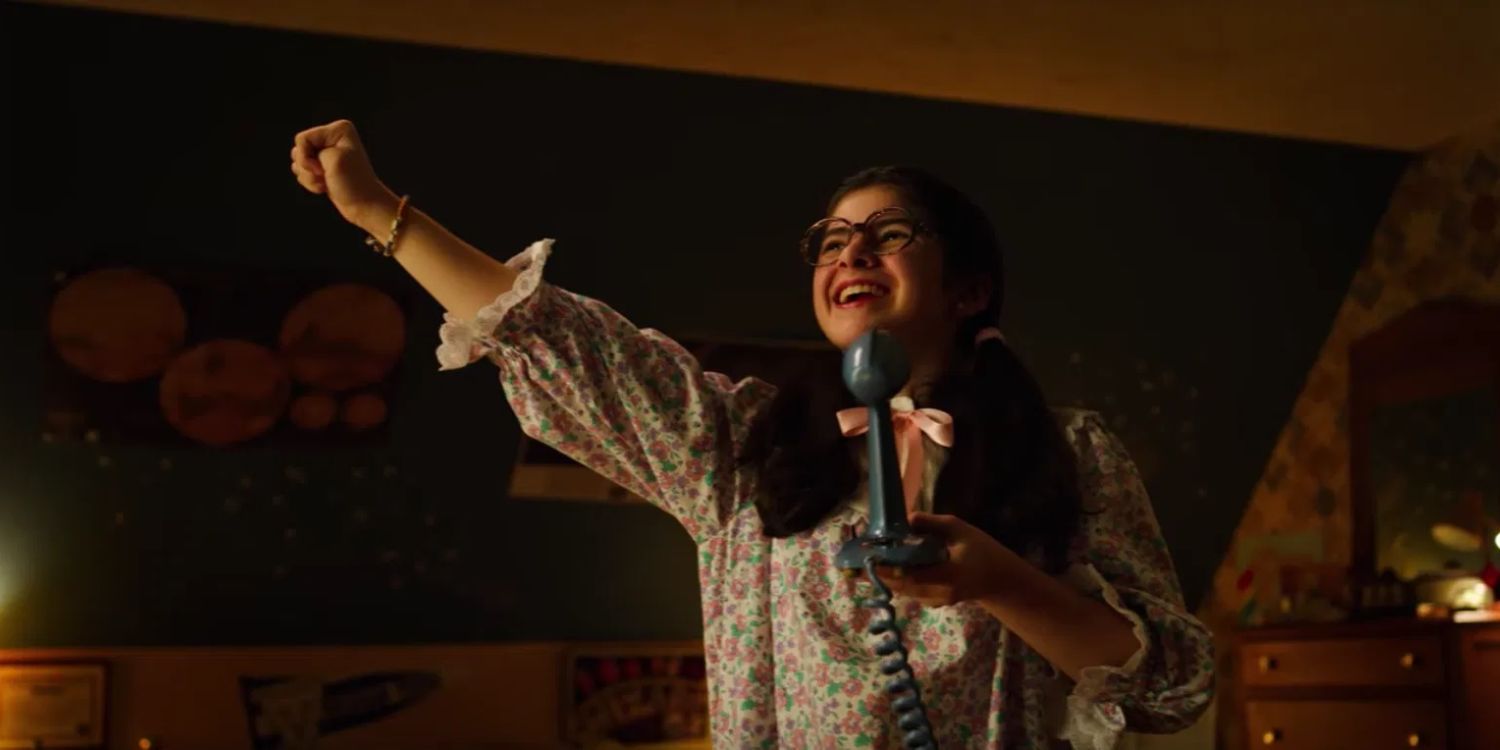 Suzie sings into a microphone and has a joyous look on her face as she raises her right arm triumphantly in &lsquo;Stranger Things&rsquo;