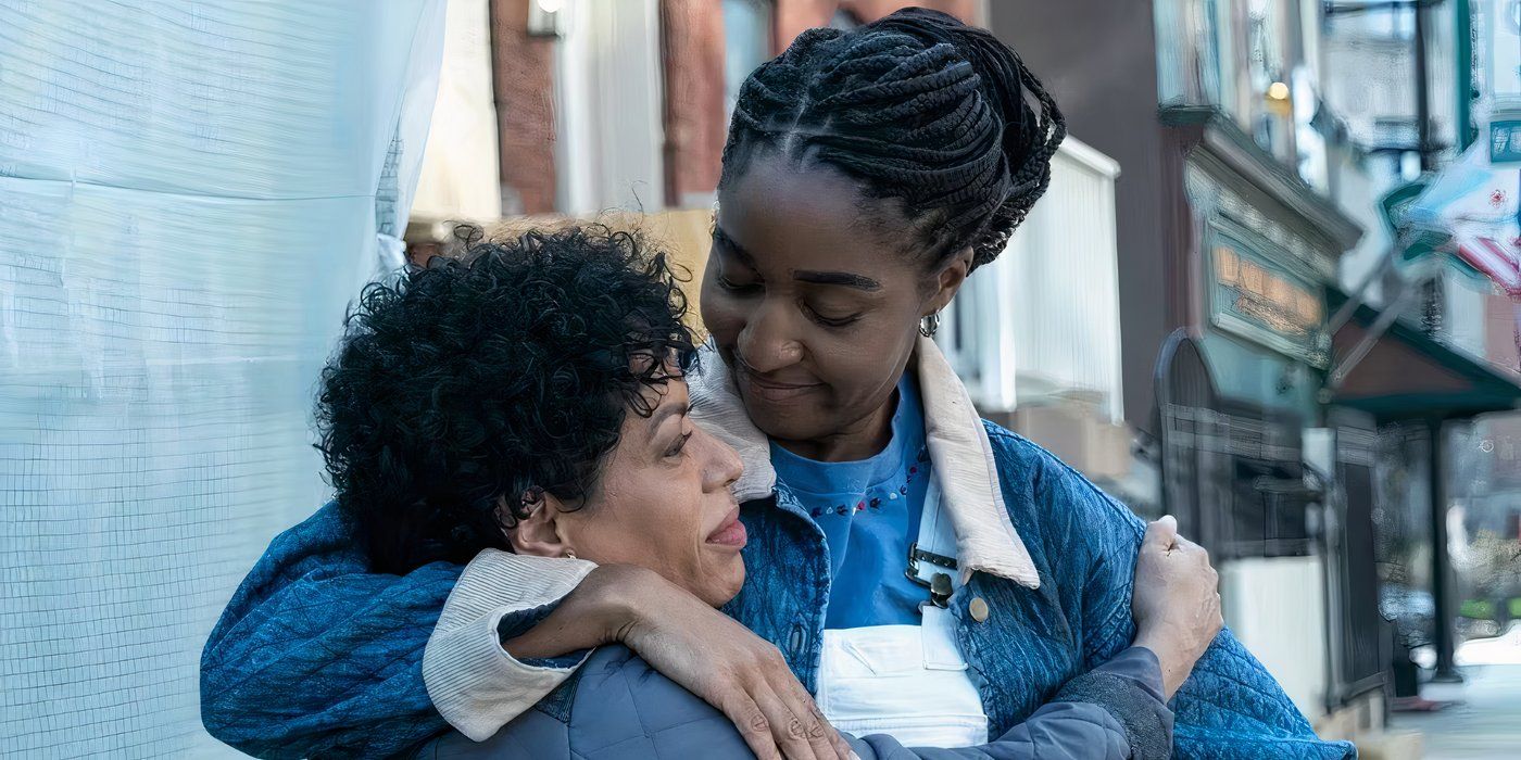 Tina (Liza-Colón Zayas) and Sydney (Ayo Edebiri) hugging each other and smiling outside in front of The Bear