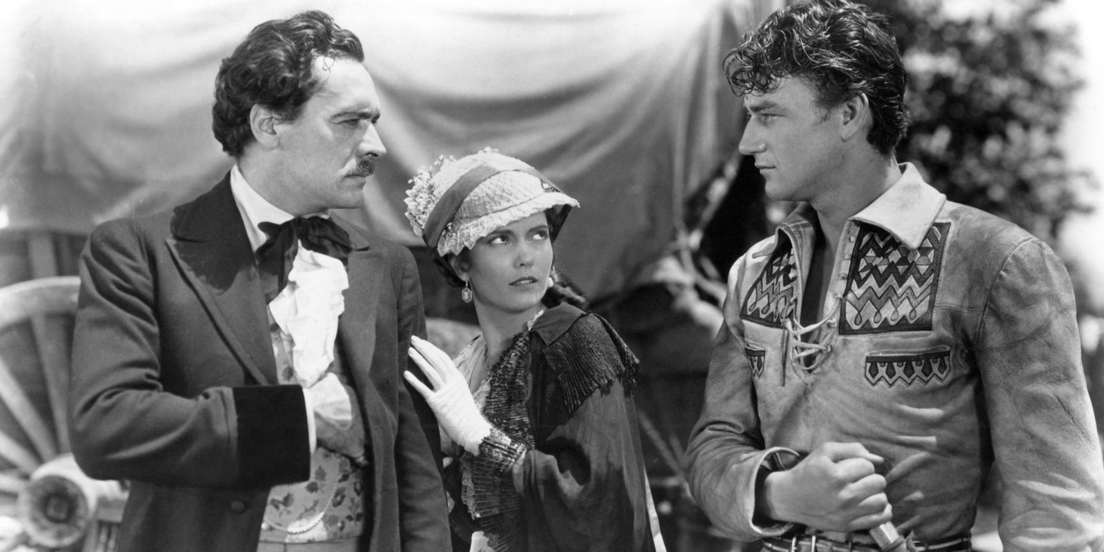 Two men face each other while a woman looks scared in The Big Trail 1930