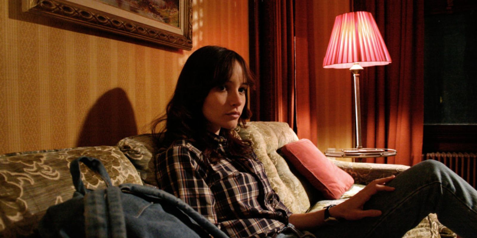 A young woman sits on the couch with a backpack