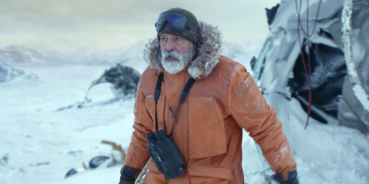 George Clooney in The Midnight Sky walking through the snow in an orange coat