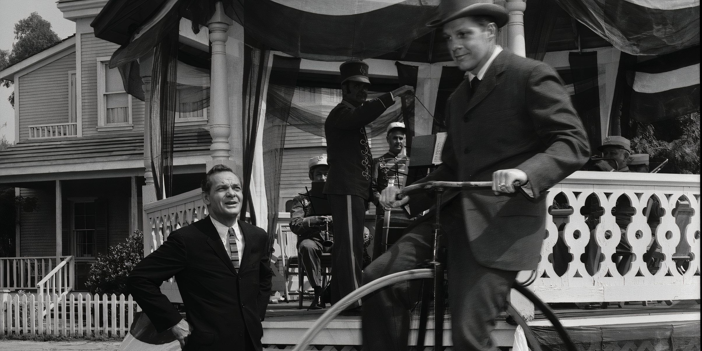 a-man-in-a-suit-watches-a-man-on-a-penny-farthing