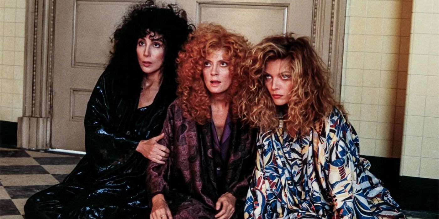 Three women, all of them witches, sit huddled together on a tiled floor in &lsquo;The Witches of Eastwick&rsquo; (1987).