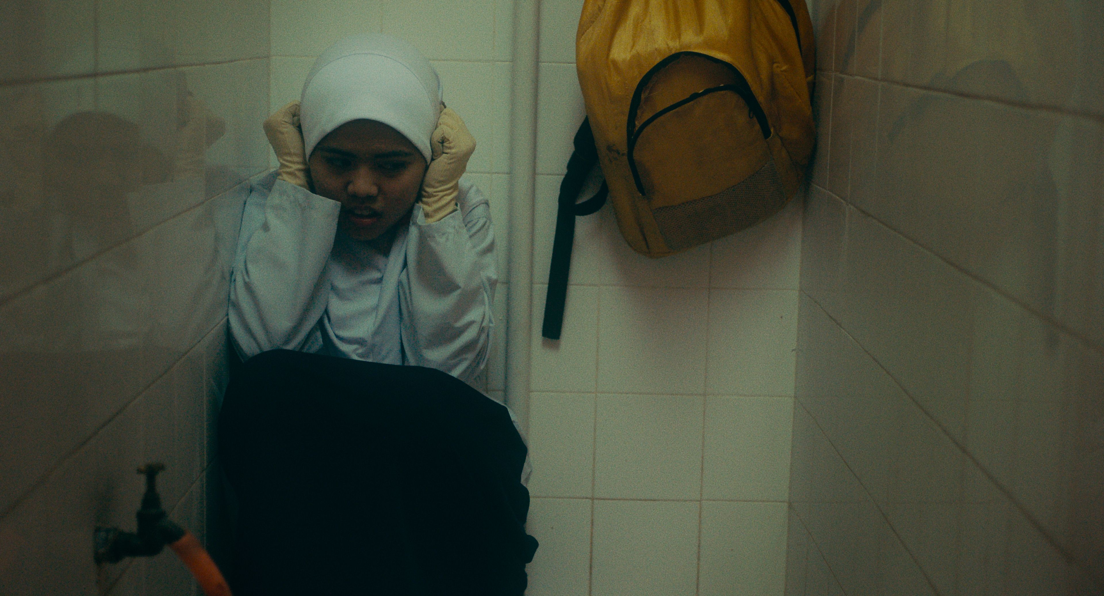 A young girl hides in a bathroom. 