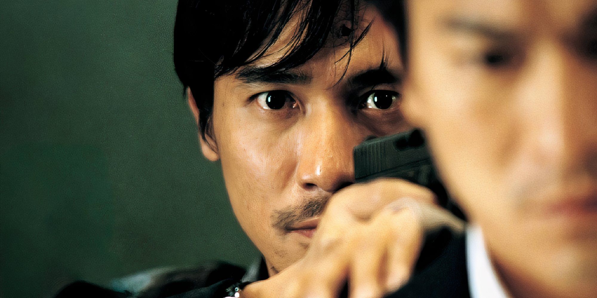 Tony Leung Chiu-wai, que interpreta a Zhang Wing-yang en Infernal Affairs, se esconde detrás de un hombre.