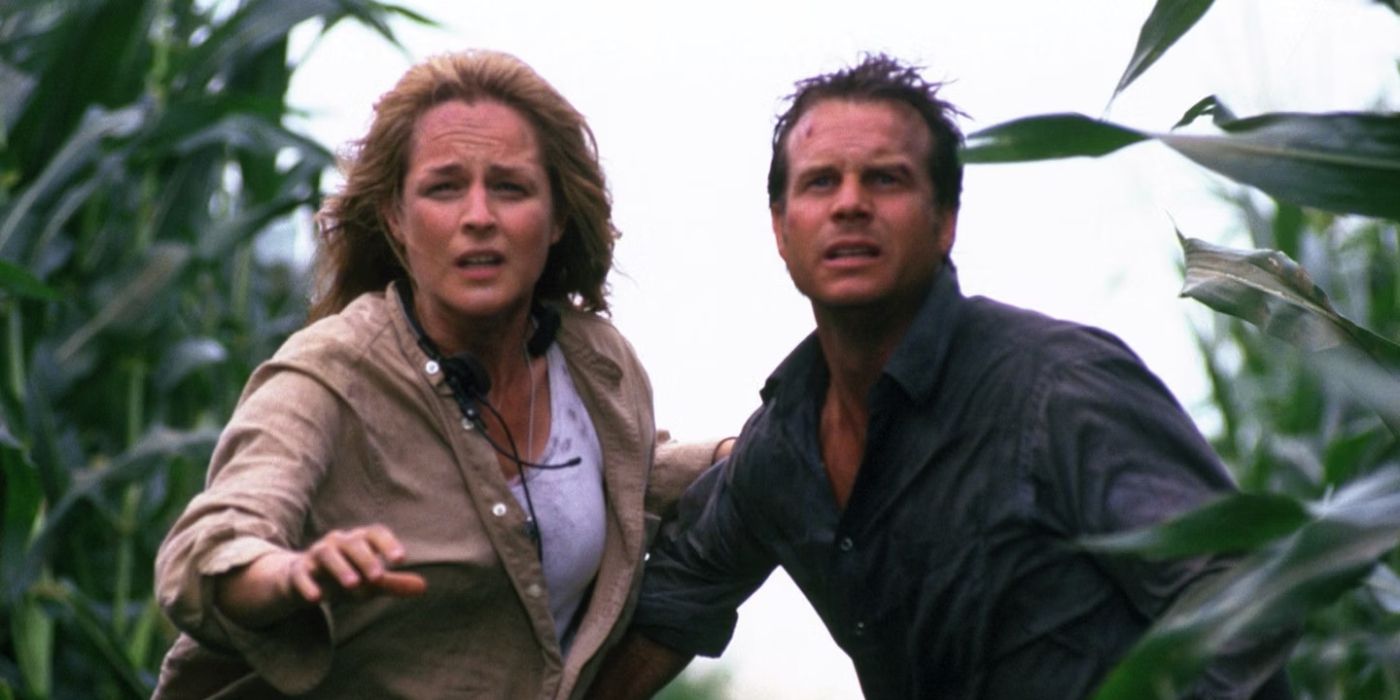 Jo (Helen Hunt) and Bill Harding (Bill Paxton) standing in a corn field staring ahead with concerned expressions and Jo reaching her hand forward in Twister