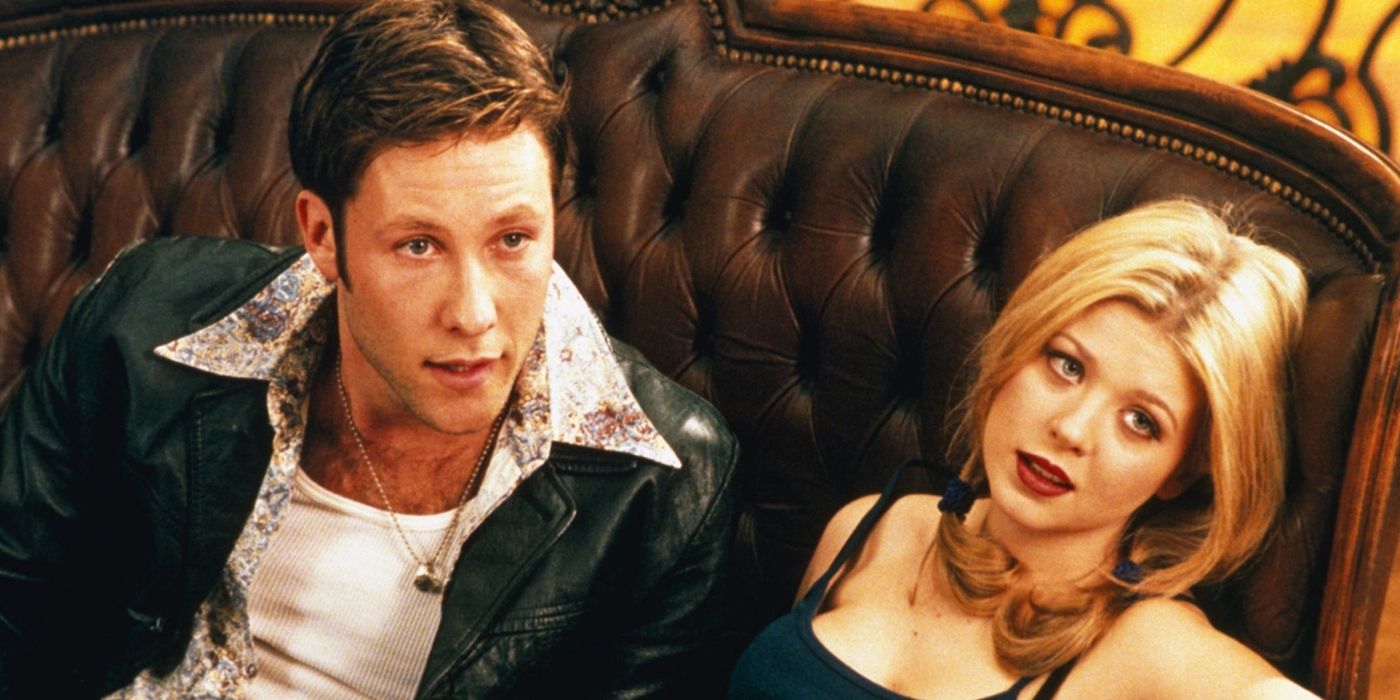 Michael Rosenbaum and Tara Reid sitting together on a couch in Urban Legend