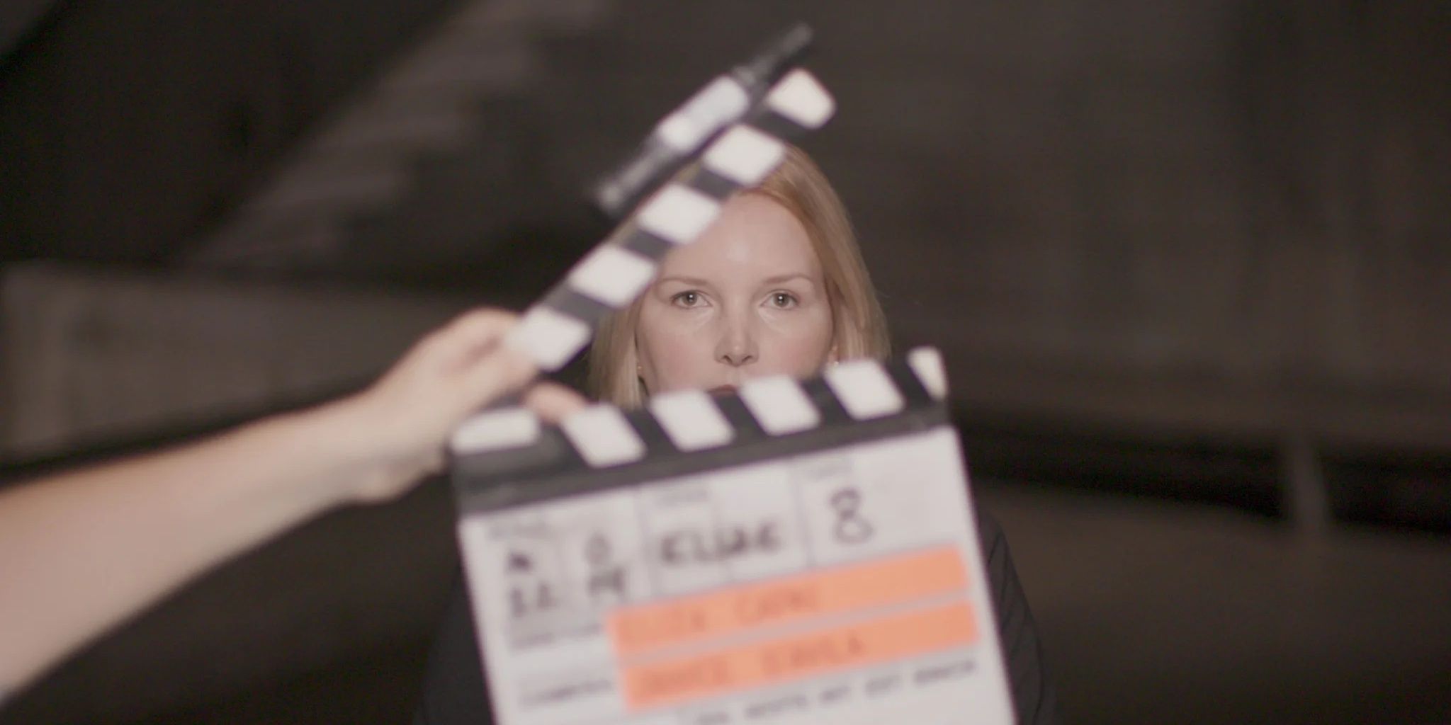 Elize Matsunaga sits in front of a clapperboard in Elize Matsunaga: Once Upon a Crime