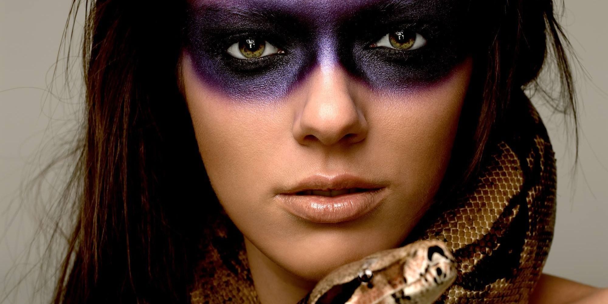 A closeup of Adrianne Curry with stylized purple eye makeup posing with a real snake on America's Next Top Model. 