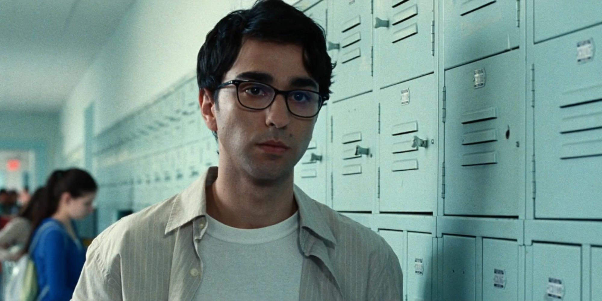 Alex Wolff wearing glasses and standing in front of school lockers in Bad Education