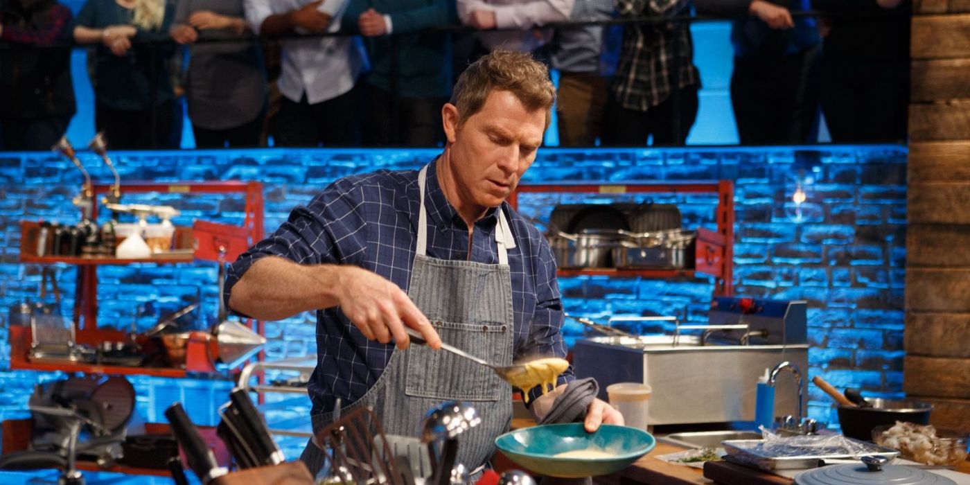 Bobby Flay wears an apron and cooks with people watching in the background on Beat Bobby Flay.