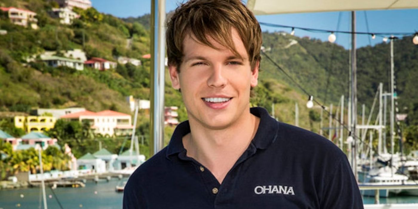 Andrew Sturby poses for a photo in a work uniform polo t-shirt with boats in the background on Below Deck.