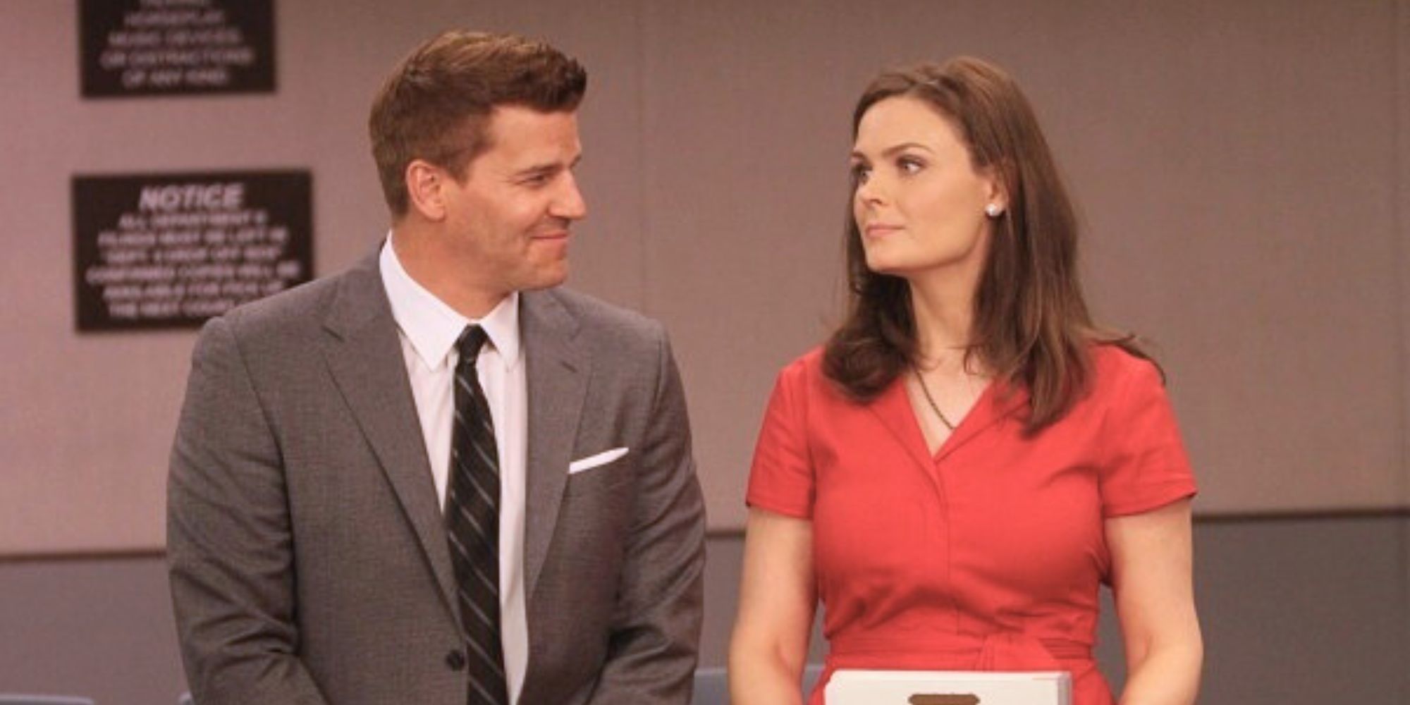 David Boreanaz smiling while standing next to Emily Deschanel in Bones.