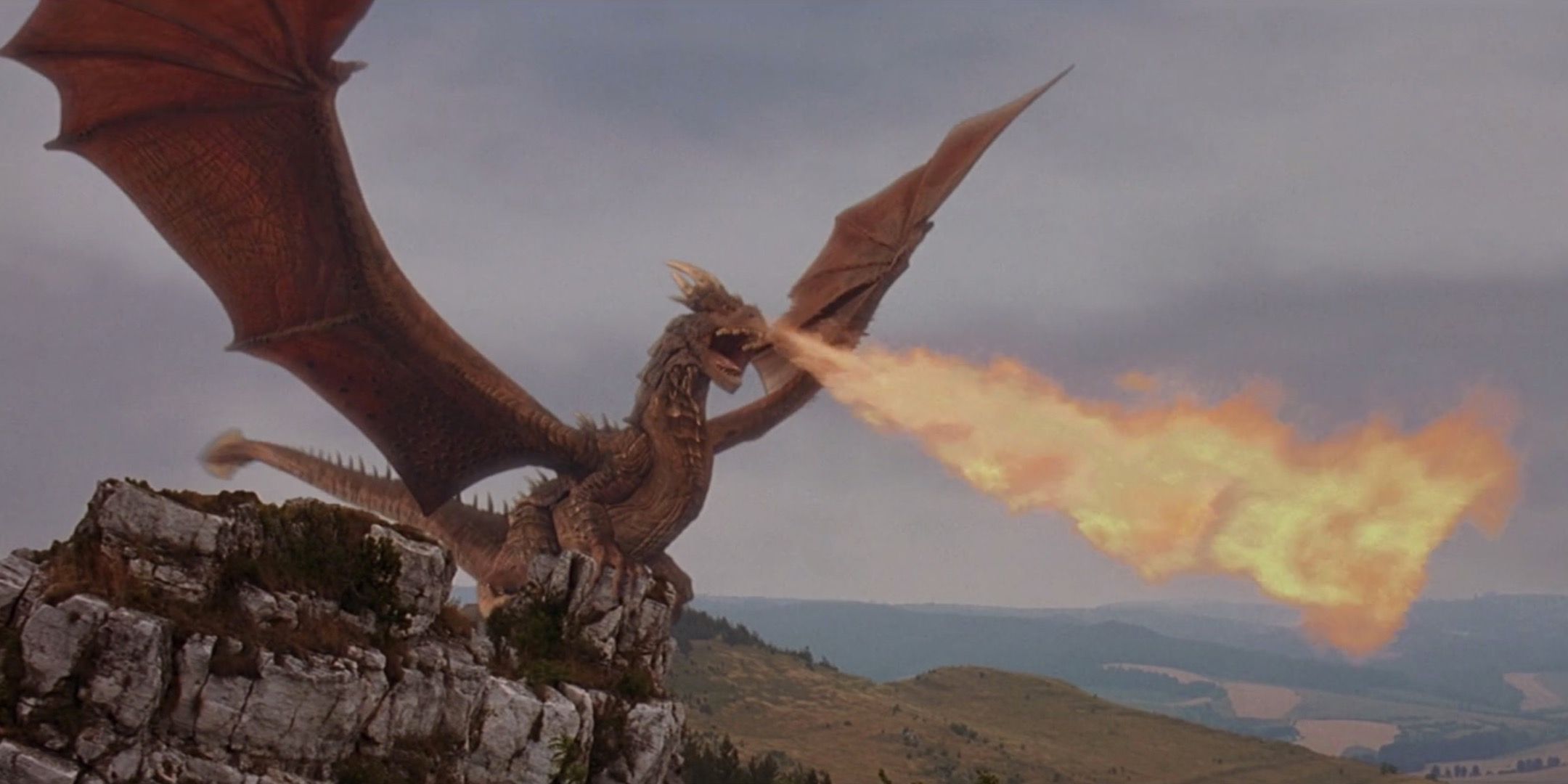 Dragonheart - Dramatic long shot of Draco perched on a rock and framed against the sky, breathing flames