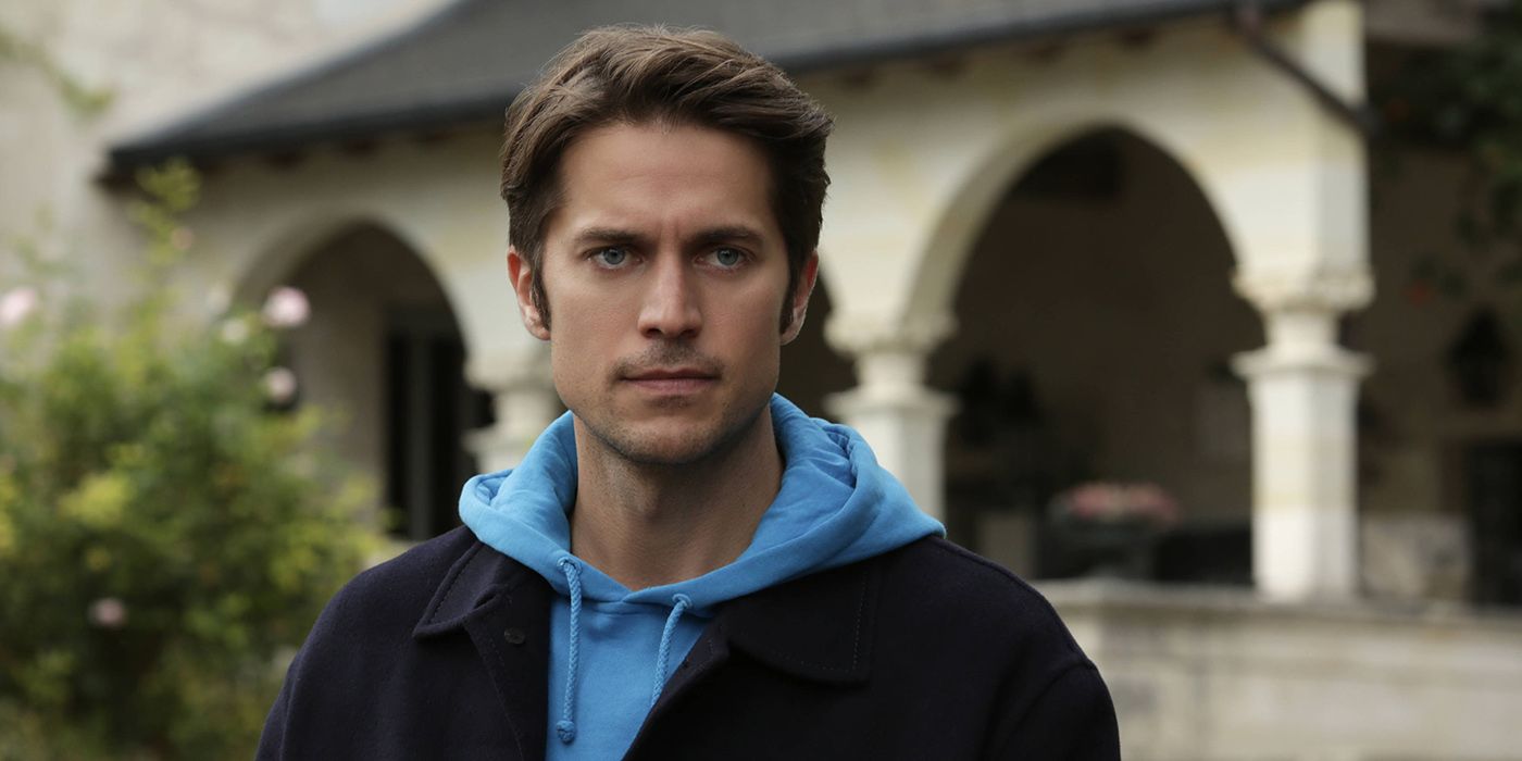 Gabriel standing with a blue hoodie looking serious in Emily in Paris.