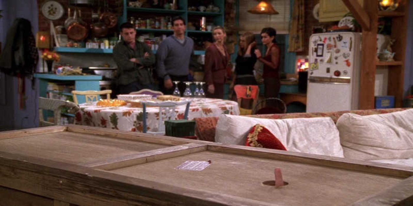Chandler sticking a finger out of a hole in a box as his friends look from afar in 'Friends'.