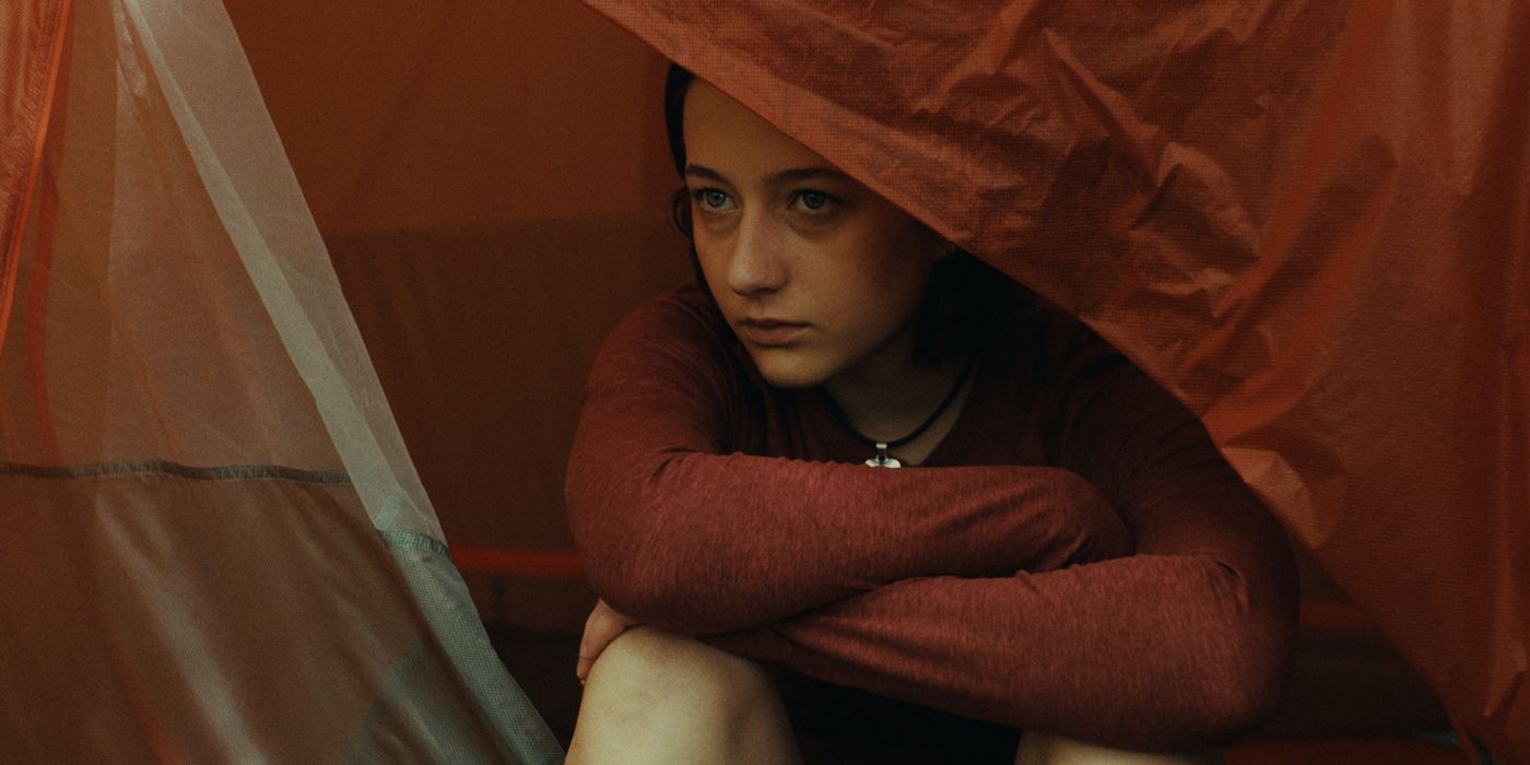 Lily Collias as Sam peers out of a tent while out in the woods in Good One. 