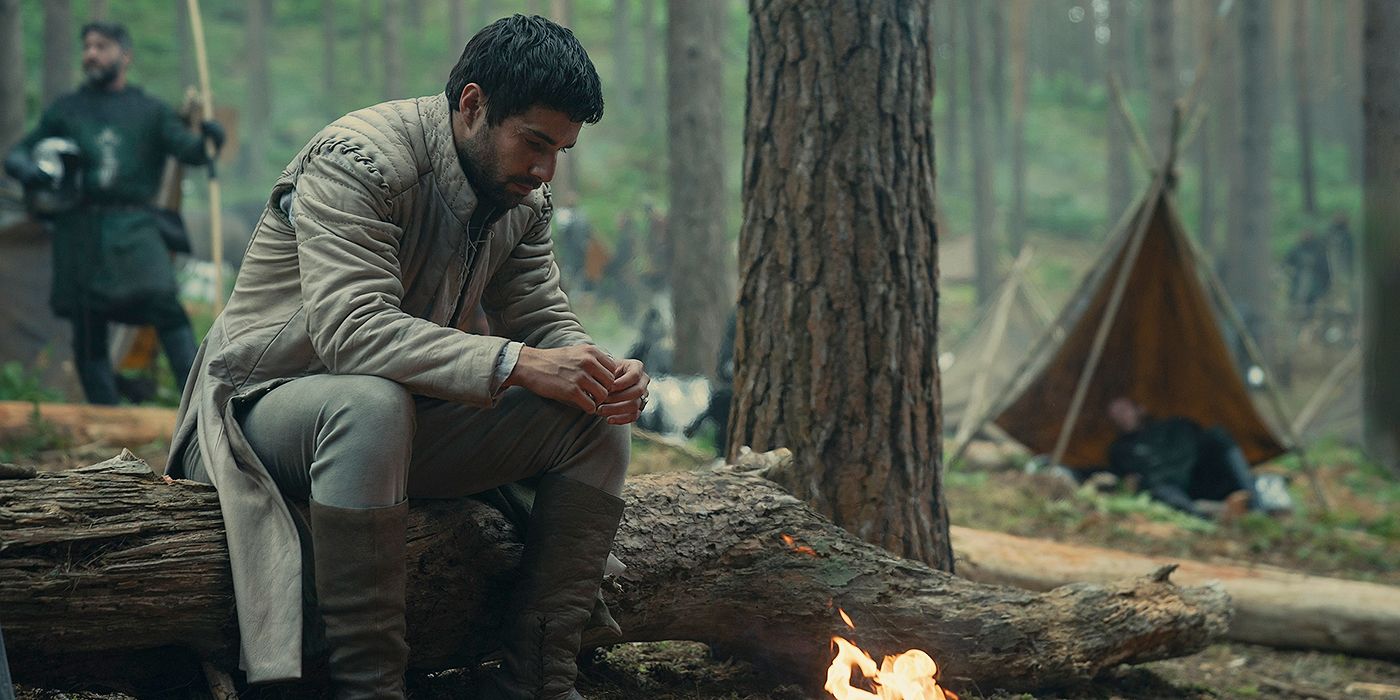 Fabien Frankel as Criston sitting on a log in front of a fire in House of the Dragon Season 2 Episode 8