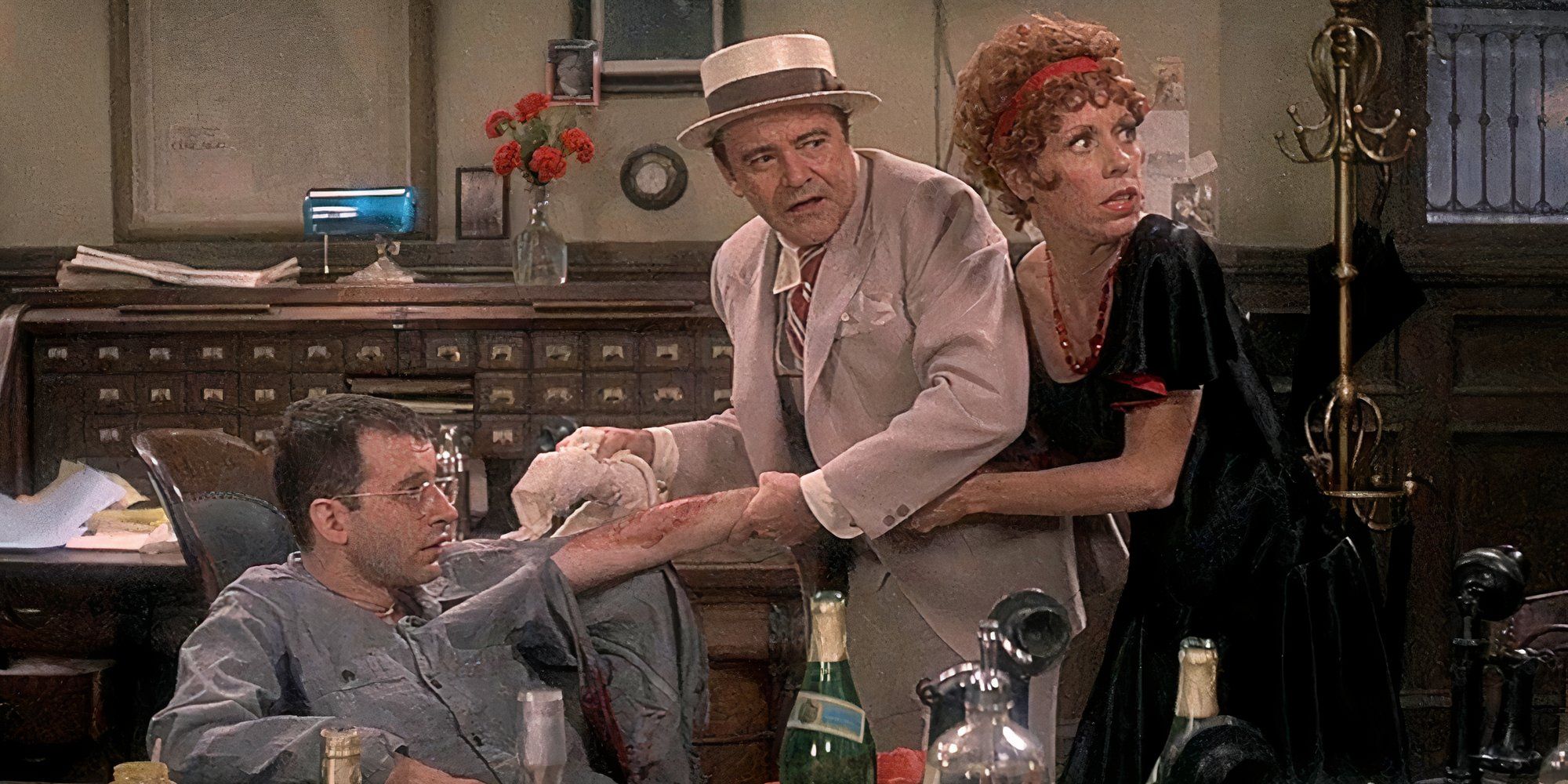 Carol Burnett clinging to Jack Lemmon cleaning Austin Pendleton's arm while he sits in a chair in The Front Page (1974)