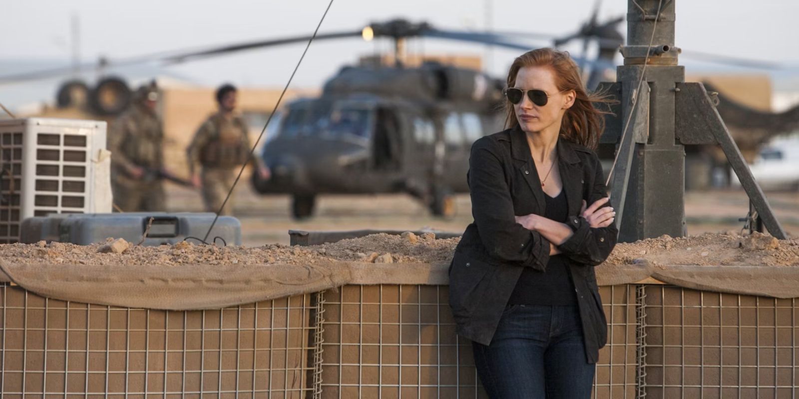 Maya apoyada en la valla y mirando hacia la derecha en Zero Dark Thirty