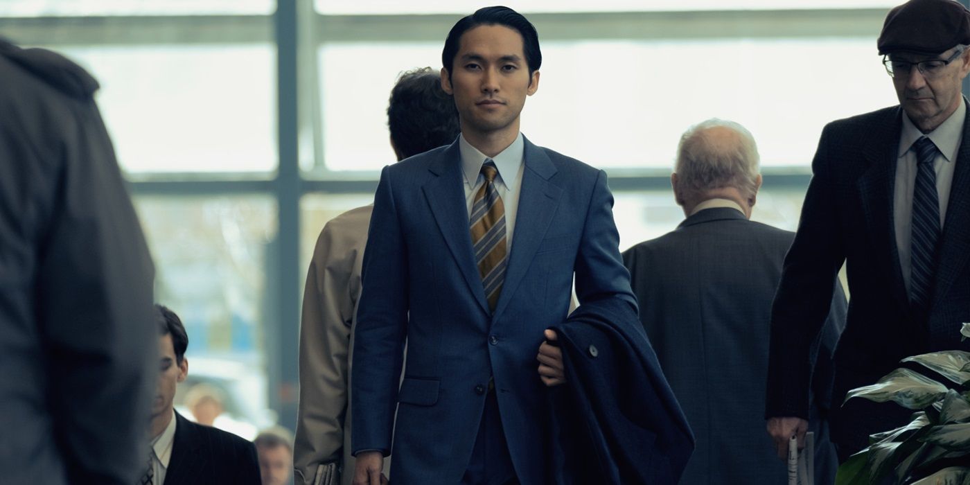 Jin Ha, walking while wearing a suit, as Solomon Baek in Pachinko Season 1