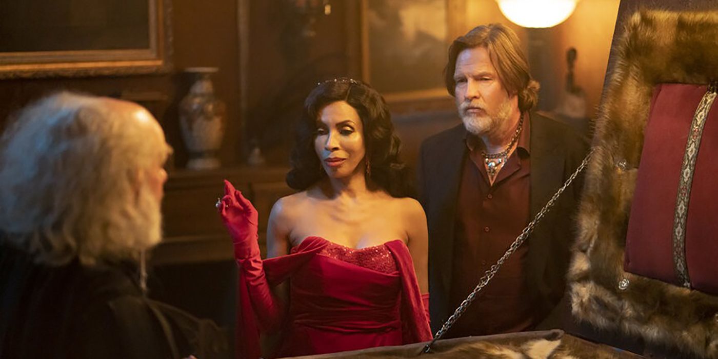 Khandi Alexander in a red dress standing with two men in a scene from What We Do in the Shadows