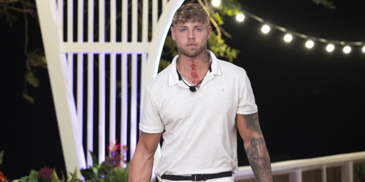 Kane Bacon sale de la villa de Love Island USA vistiendo una camisa y pantalones blancos.