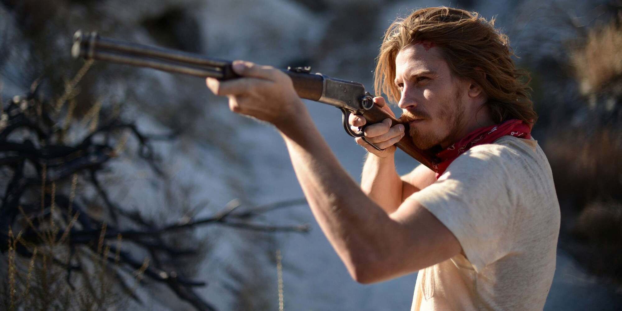 Thomas wearing a red bandana around his neck and aiming down the sights of a rifle in &lsquo;Mojave&rsquo; (2015)