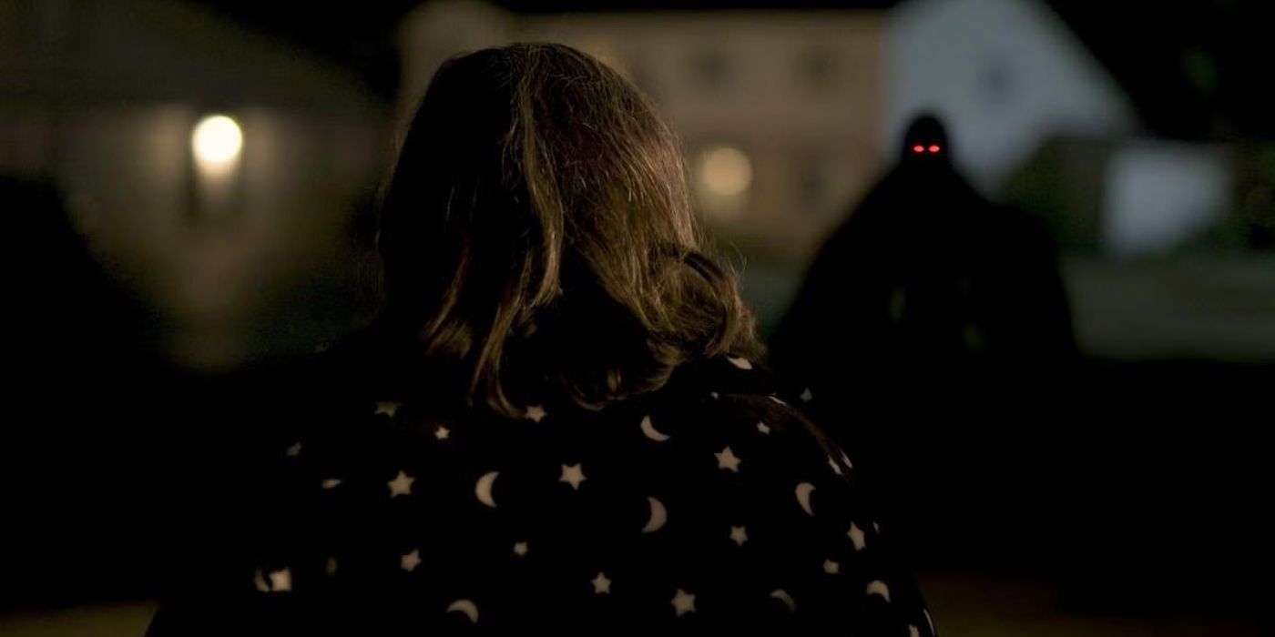 A woman stares at a silhouette with red eyes at night