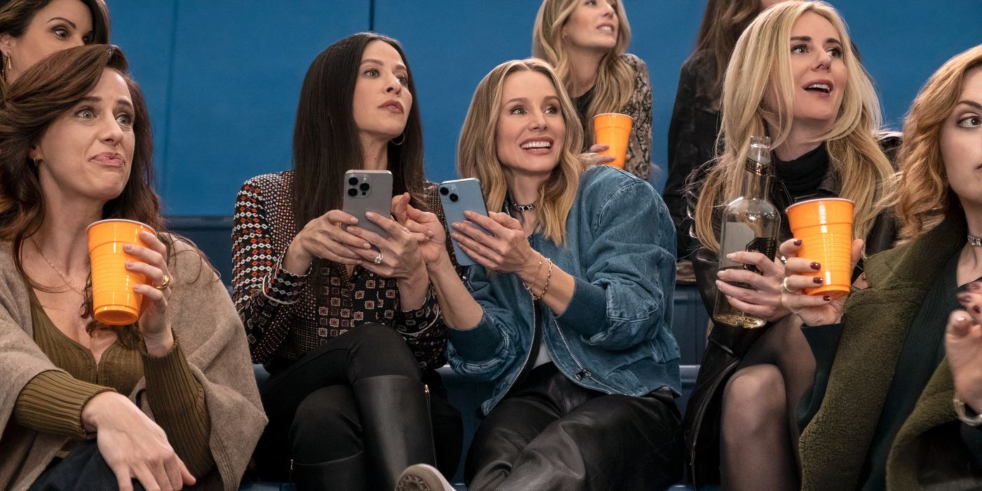 Kristen Bell wears a jean jacket and has her phone out while smiling and talking to jackie tohn