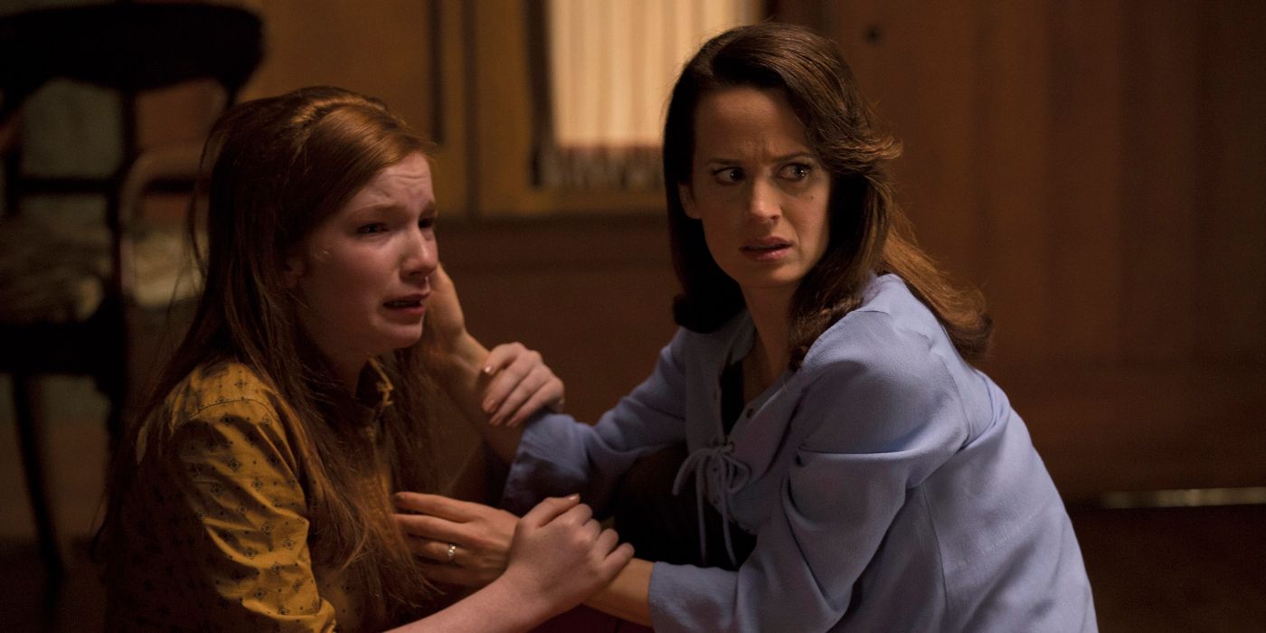 Alice (Elizabeth Reaser) looking over her shoulder to the right and kneeling close to a terrified Lina (Annalise Basso) in Ouija: Origin of Evil