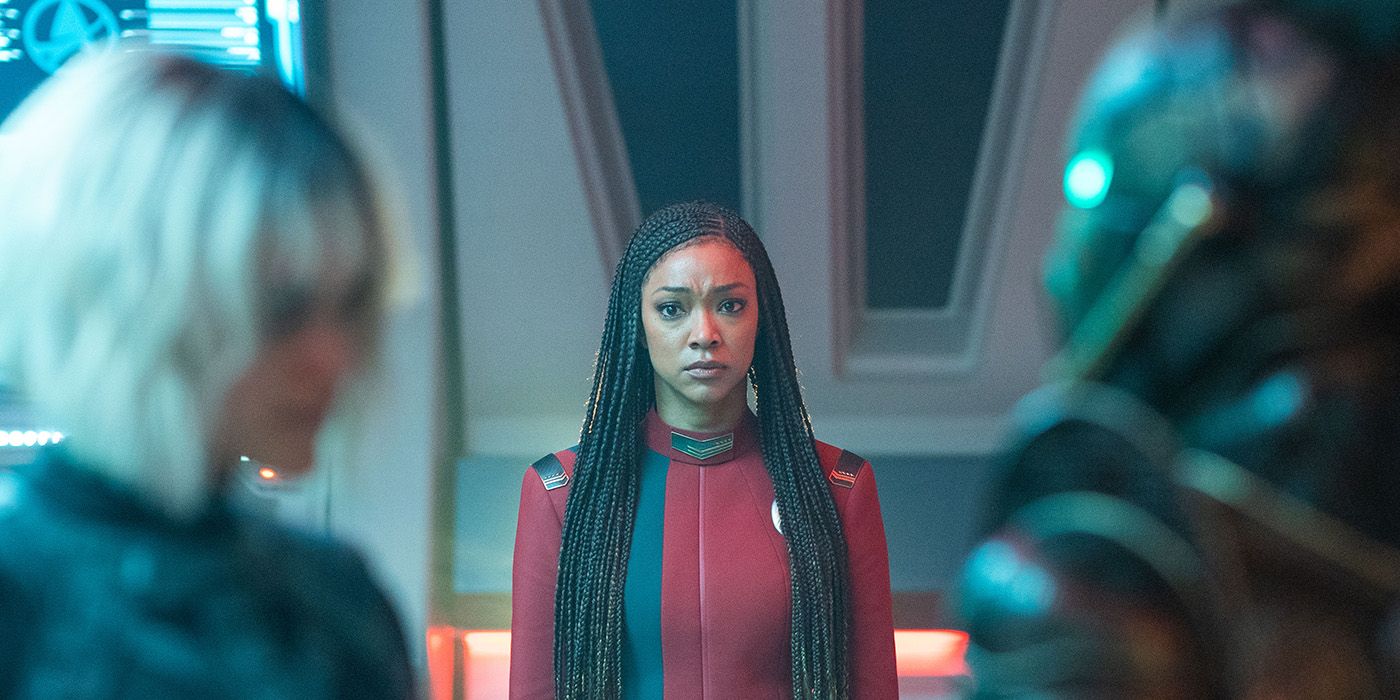 Sonequa Martin Green between two blurry figures in Star Trek Discovery