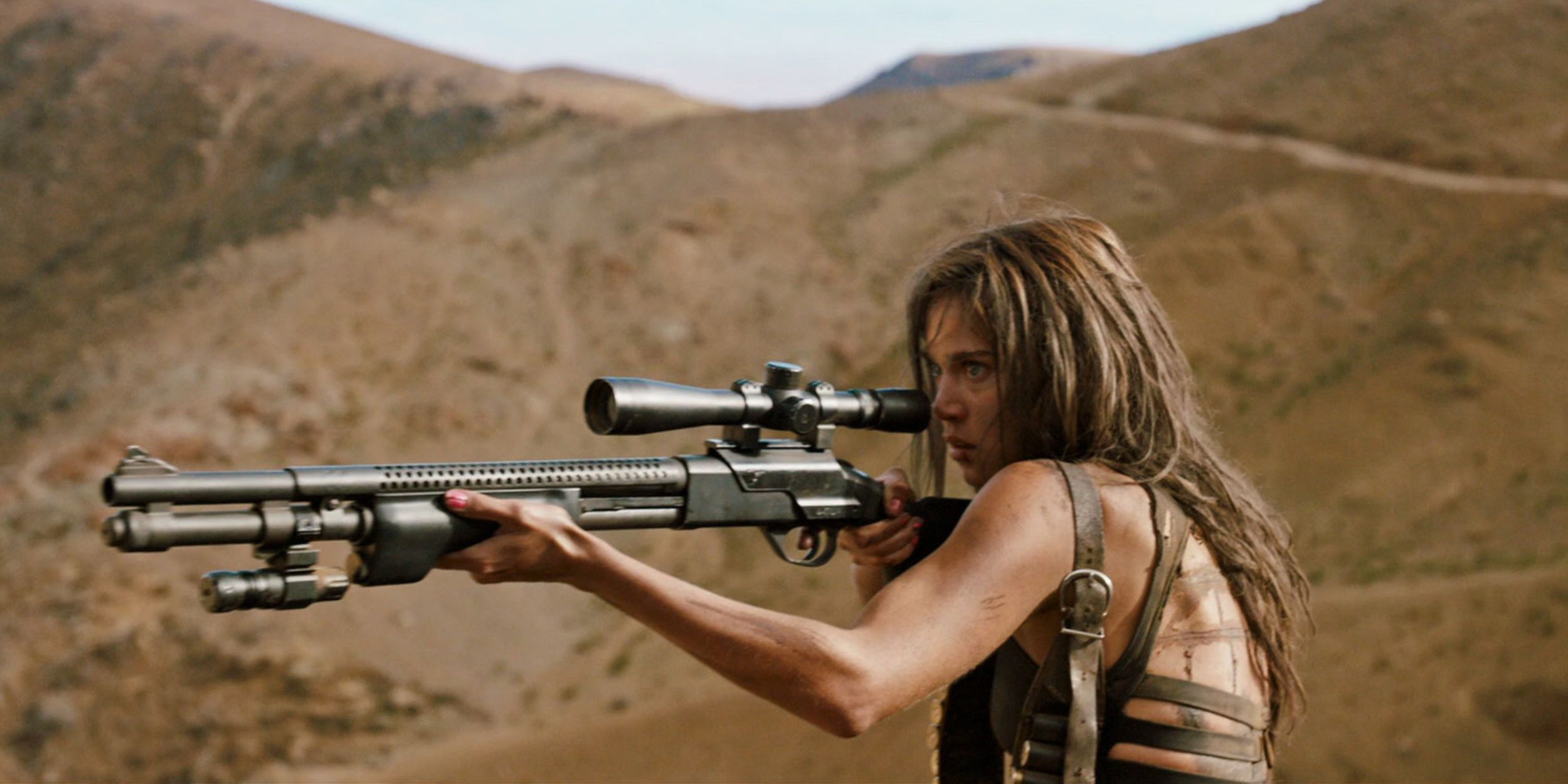 A woman in the desert aiming a gun in Revenge