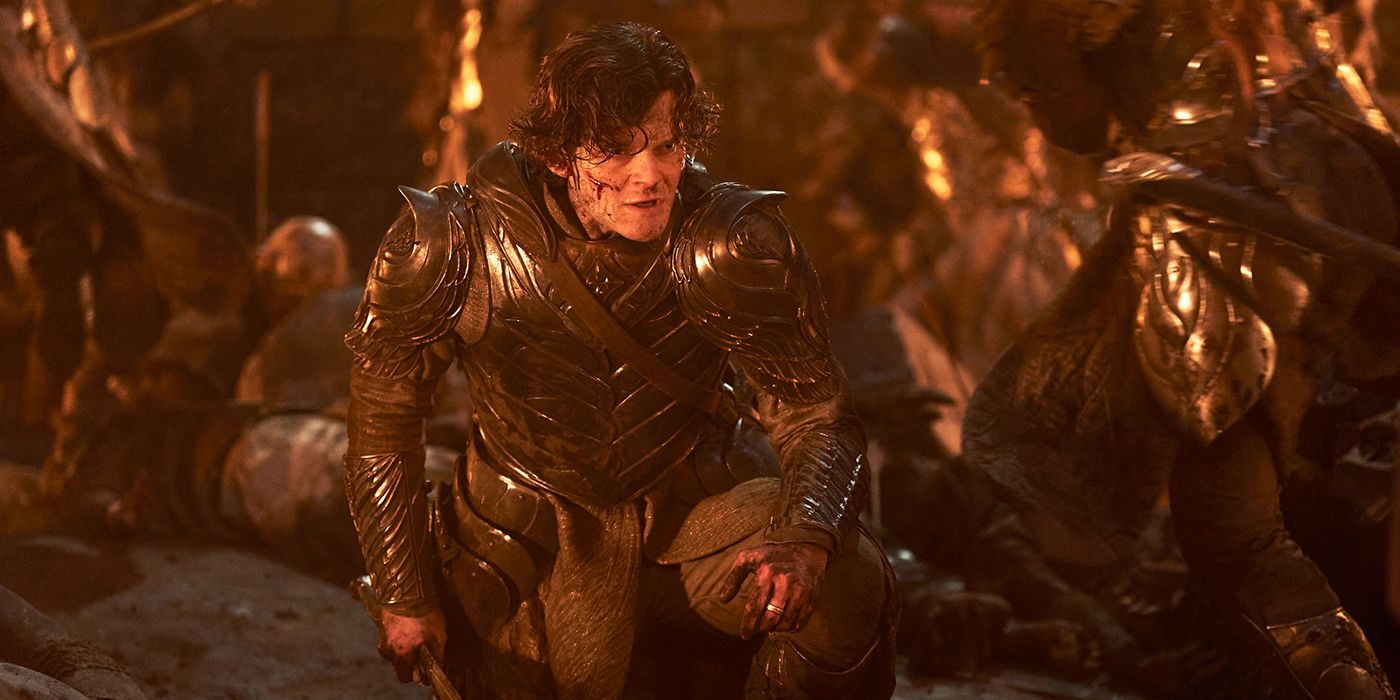 Robert Aramayo as Elrond fighting in battle with blood on his face and wearing armor while crouching in The Lord of the Rings: The Rings of Power Season 2