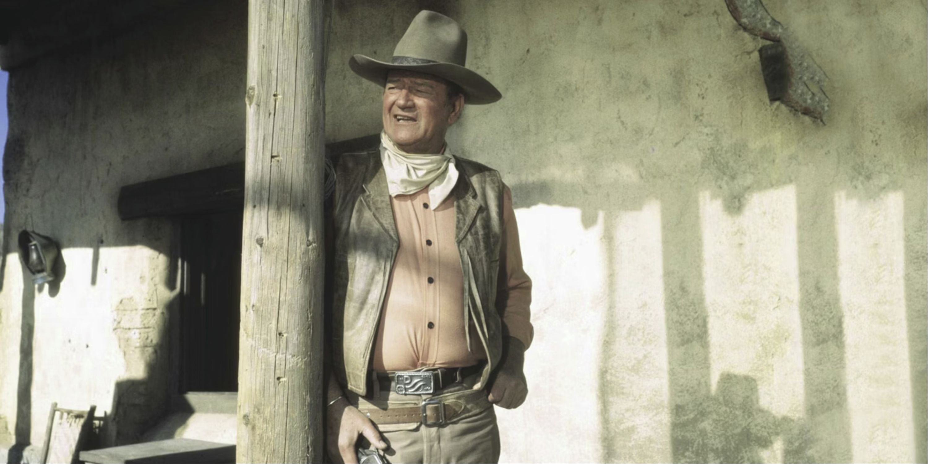 John Wayne leaning against a pole in Rio Lobo