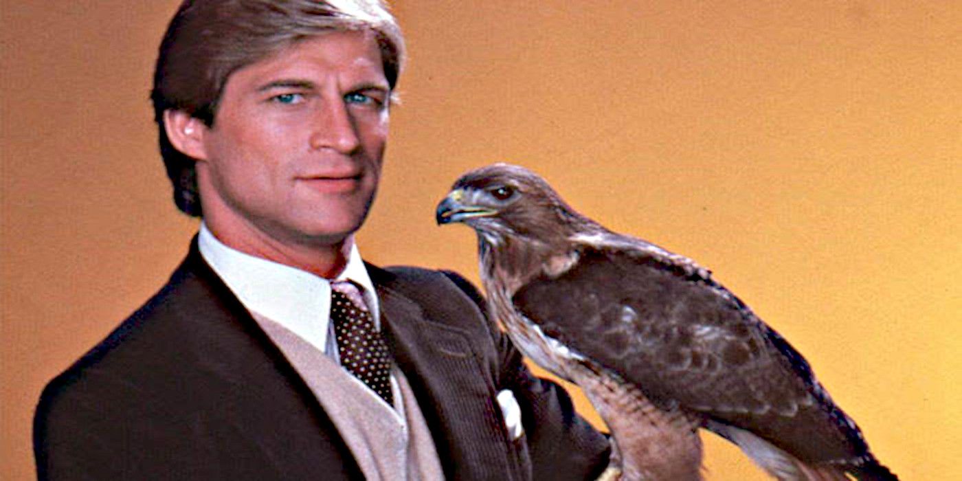 Dr. Jonathan Chase wearing a jacket and tie sits with a falcon on his arm