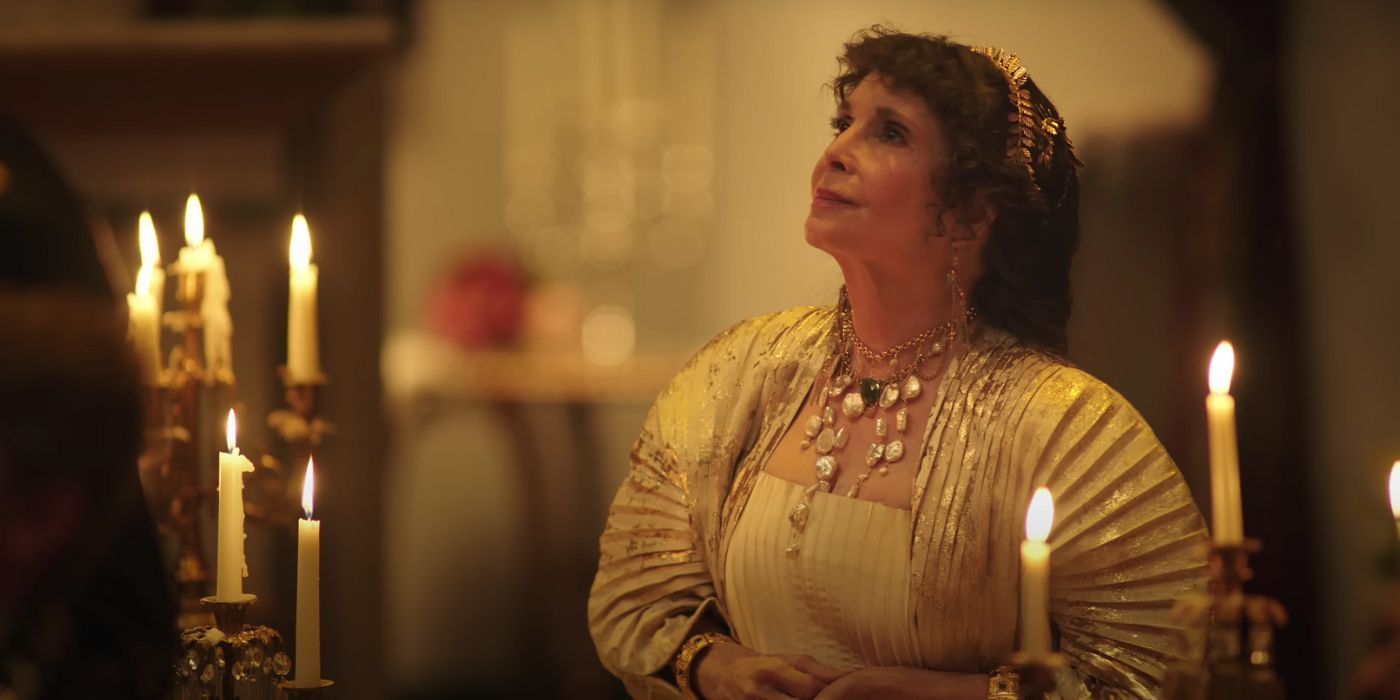 Talia Shire sitting at a candlelit table looking up in Megalopolis