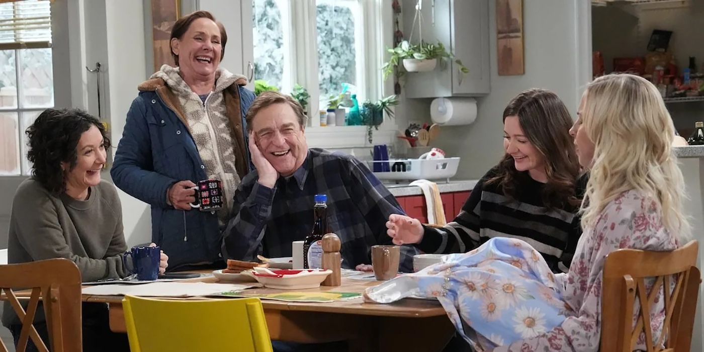 Darlene, Jackie, Dan, Harris, and Becky sitting around a kitchen table smiling and laughing on The Conners