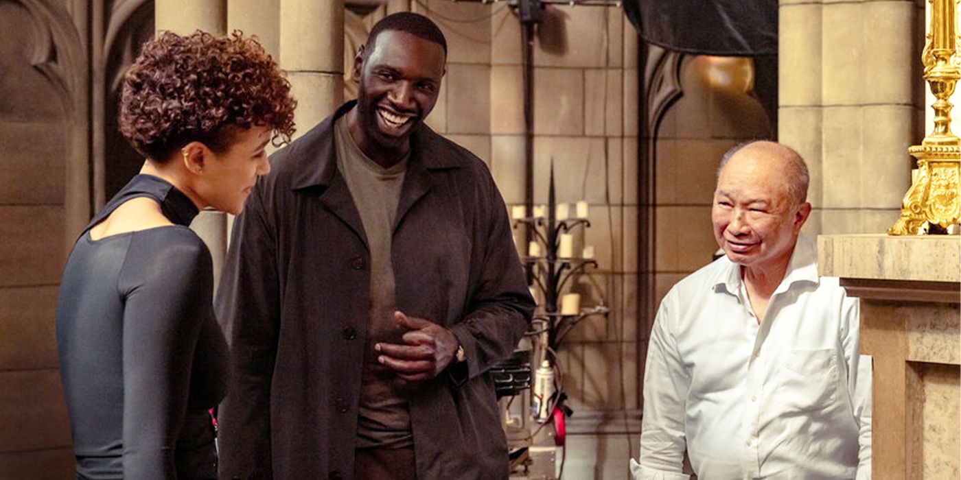 Nathalie Emmanuel, Omar Sy and John Woo smile and chat on the set of The Killer 